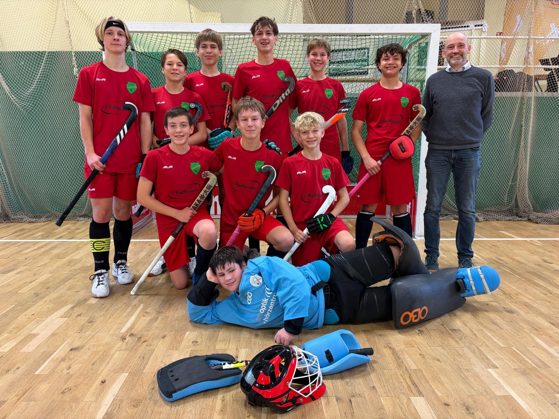 Gruppe von Kindern in roten T-Shirts beim Sport, mit Bällen und Hütchen.