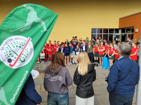 Spieler bei der Siegerehrung mit roten Trikots und dem grünem EHC-Banner