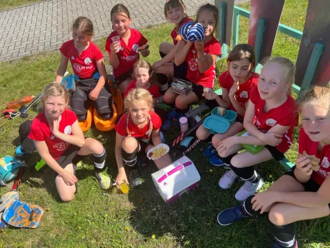 Gruppe von Kindern in roten T-Shirts draußen spielend.