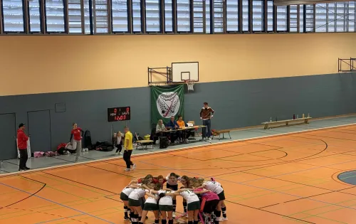 Sporthalle mit Basketballkörben und Tischen auf dem Boden.