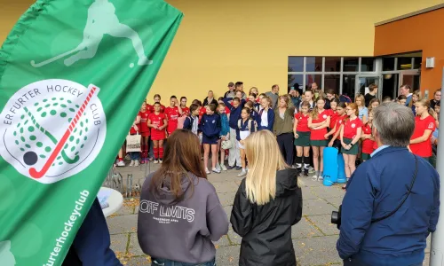 Spieler bei der Siegerehrung mit roten Trikots und dem grünem EHC-Banner